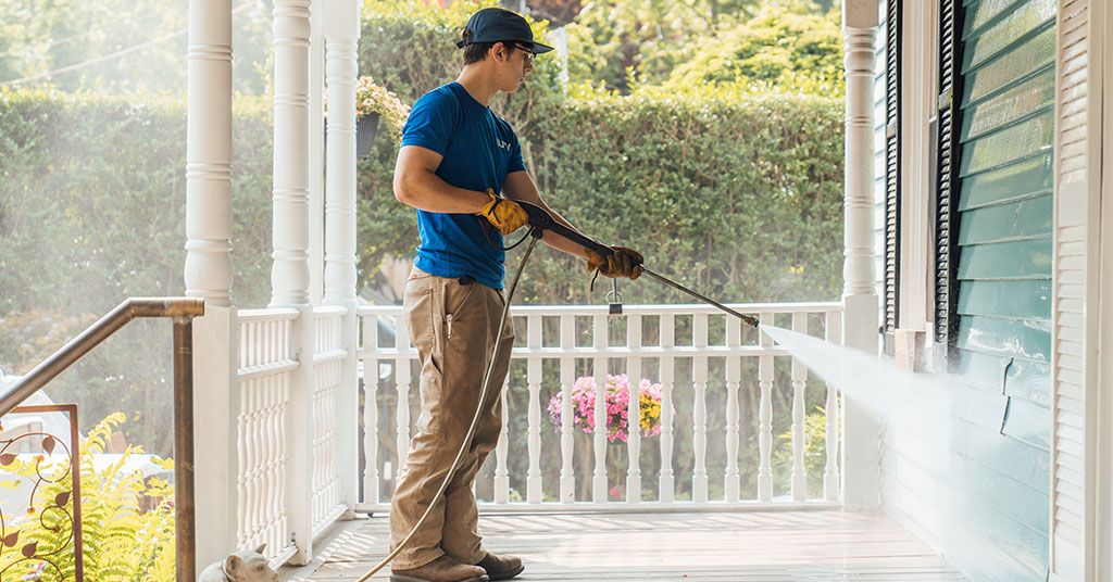man pressure washing a house